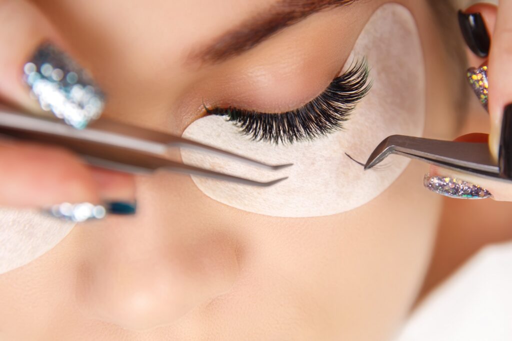 Eyelash Extension Procedure. Woman Eye with Long Eyelashes. Close up, selective focus.